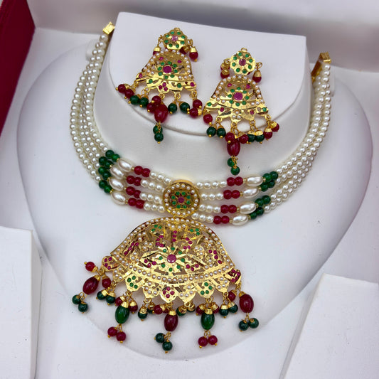 Gold-plated Indian traditional jewelry set featuring a multi-strand pearl choker necklace, a large matching pendant, and matching earrings, embellished with red and green stones.